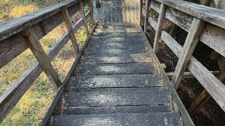 Wood deck staircase darkened with dirt and mildew before pressure washing in Bellevue, WA