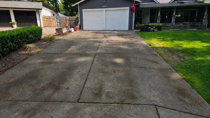 Concrete driveway with dark, grimy staining before pressure washing in Issaquah, WA