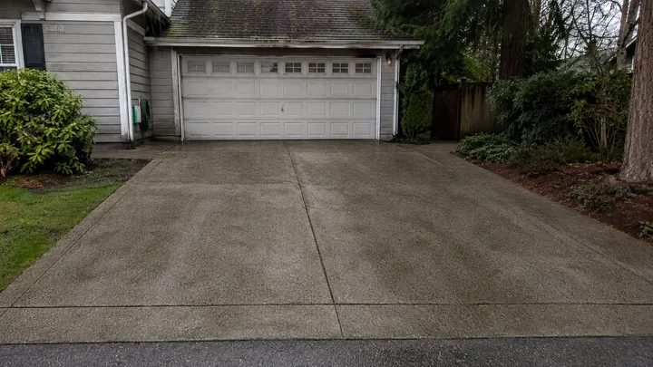 Concrete driveway stained with moss and grime before pressure washing in Sammamish, WA