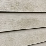 House siding with algae and grime buildup before washing